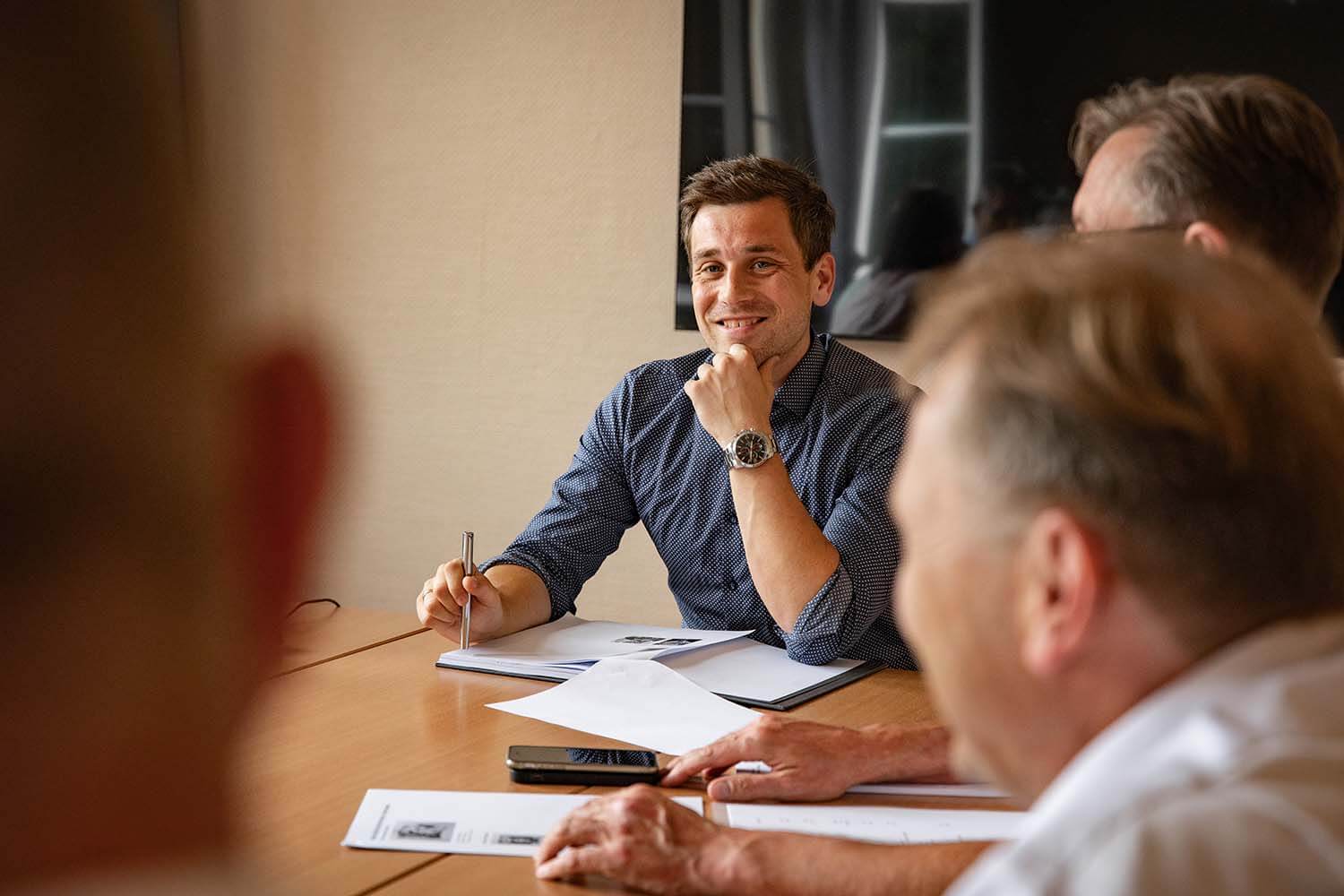 Lächelnde Personen sitzen an einem Konferenztisch